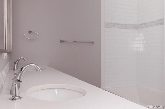 bathroom with tiled shower and sink