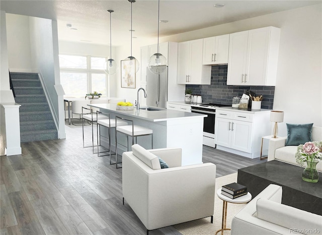 kitchen with a center island with sink, white cabinets, white range oven, decorative light fixtures, and dark hardwood / wood-style flooring