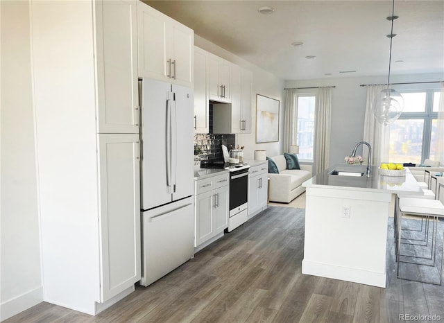 kitchen with white cabinetry, white appliances, an island with sink, and hanging light fixtures