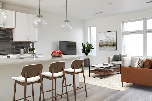 kitchen featuring a wealth of natural light, light hardwood / wood-style flooring, white cabinetry, and hanging light fixtures