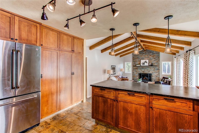 kitchen with pendant lighting, vaulted ceiling with beams, stainless steel fridge, and a textured ceiling