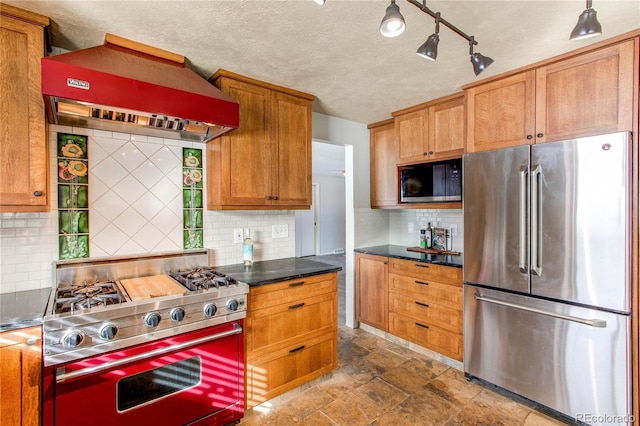 kitchen with tasteful backsplash, a textured ceiling, wall chimney range hood, and appliances with stainless steel finishes