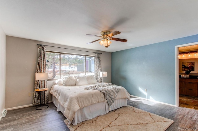 bedroom featuring dark hardwood / wood-style flooring, ensuite bathroom, and ceiling fan