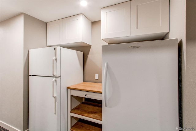 kitchen featuring white cabinetry and white fridge