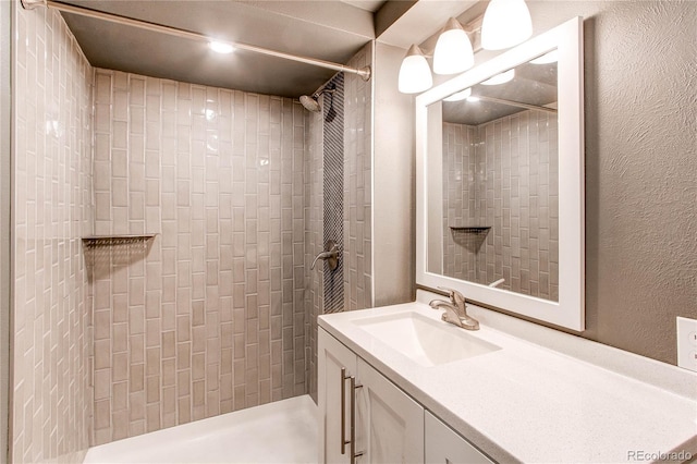 bathroom with a tile shower and vanity