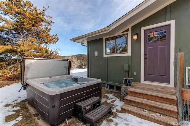 snow covered property entrance with a hot tub