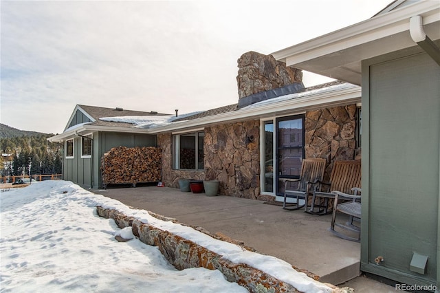 snow covered house featuring a patio area