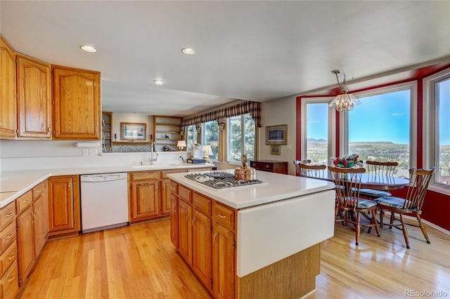 kitchen with stainless steel gas cooktop, decorative light fixtures, an inviting chandelier, dishwasher, and a center island