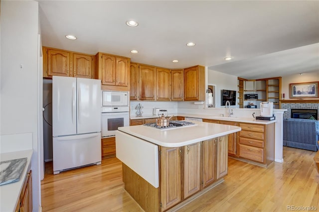 kitchen featuring kitchen peninsula, a center island, white appliances, and light hardwood / wood-style flooring