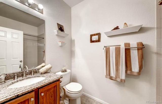 bathroom featuring vanity, toilet, and a tile shower