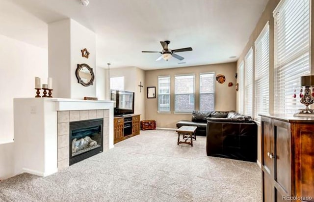 living room featuring light colored carpet, ceiling fan, and a tile fireplace