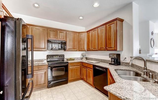 kitchen featuring black appliances, light stone countertops, kitchen peninsula, and sink