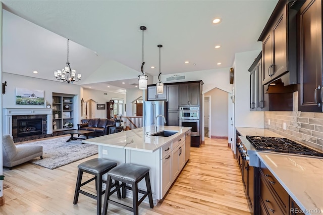 kitchen with a sink, open floor plan, light wood finished floors, lofted ceiling, and backsplash