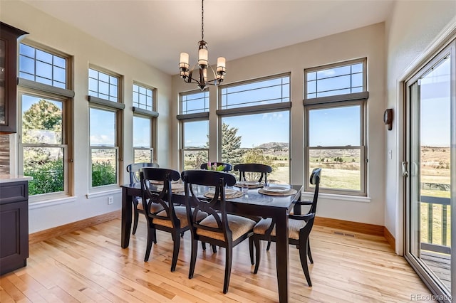 dining room with baseboards, a chandelier, and light wood-type flooring