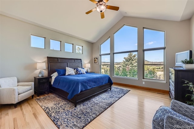 bedroom with light wood-type flooring, high vaulted ceiling, ceiling fan, and baseboards