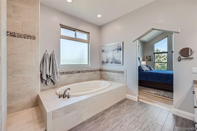 full bathroom with connected bathroom, a bath, wood finished floors, recessed lighting, and baseboards