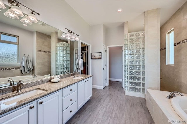 full bathroom featuring a garden tub, wood finished floors, double vanity, and a walk in shower