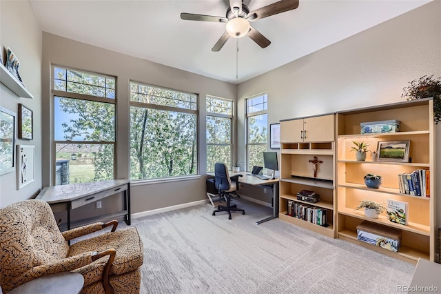 office space featuring ceiling fan, plenty of natural light, light colored carpet, and baseboards