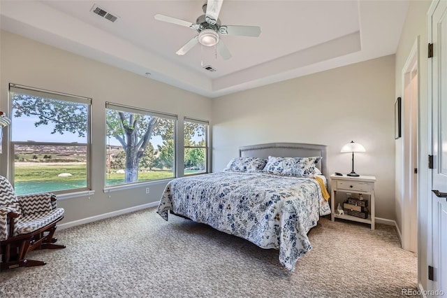 carpeted bedroom featuring baseboards, a raised ceiling, and ceiling fan
