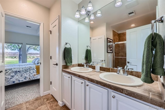 bathroom with a tile shower, connected bathroom, double vanity, and tile patterned flooring