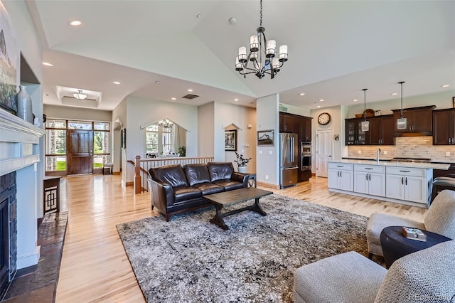 living area with a chandelier, light wood finished floors, a fireplace with flush hearth, recessed lighting, and baseboards