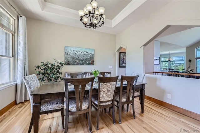dining space with a chandelier, light wood-style floors, baseboards, a tray ceiling, and ornamental molding