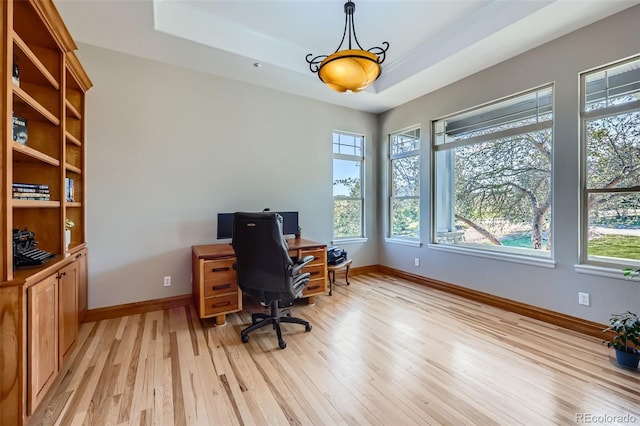 home office featuring light wood finished floors, baseboards, and a tray ceiling