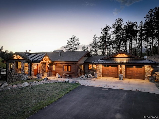 view of front of property featuring an attached garage, a standing seam roof, metal roof, stone siding, and driveway