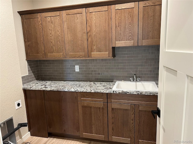 kitchen featuring tasteful backsplash, light stone countertops, and sink