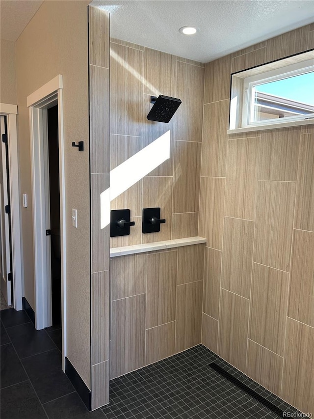 bathroom with tile patterned flooring, a tile shower, and a textured ceiling