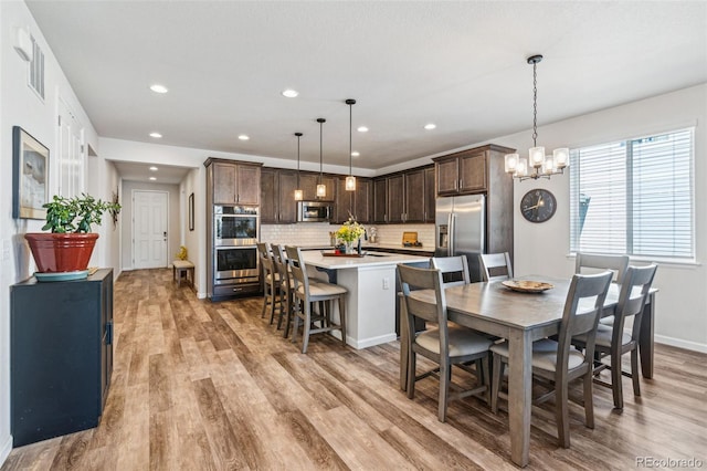 dining space featuring an inviting chandelier, baseboards, light wood-type flooring, and recessed lighting