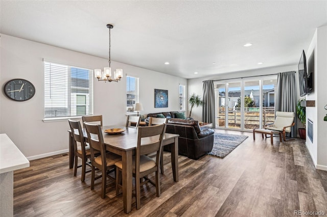 dining space with an inviting chandelier, plenty of natural light, dark wood-style flooring, and baseboards