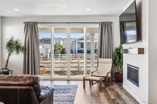 sitting room with recessed lighting, a glass covered fireplace, and wood finished floors