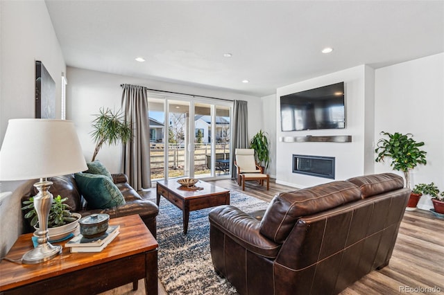 living room featuring a glass covered fireplace, recessed lighting, and wood finished floors