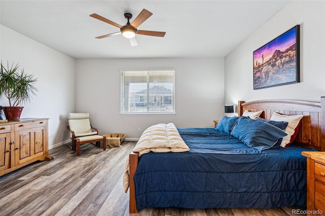 bedroom with a ceiling fan, wood finished floors, and baseboards