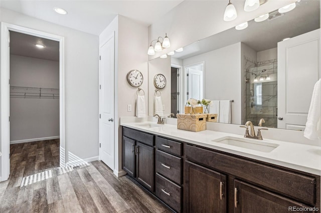 full bath with a sink, a shower stall, visible vents, and wood finished floors
