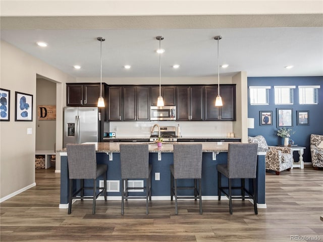 kitchen with pendant lighting, a center island with sink, and appliances with stainless steel finishes