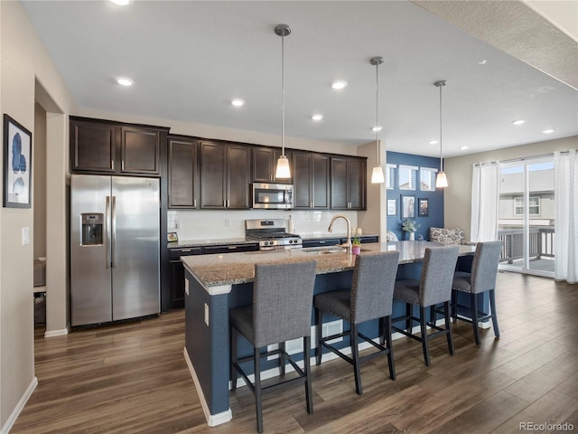 kitchen with a kitchen island with sink, hanging light fixtures, a breakfast bar area, and appliances with stainless steel finishes