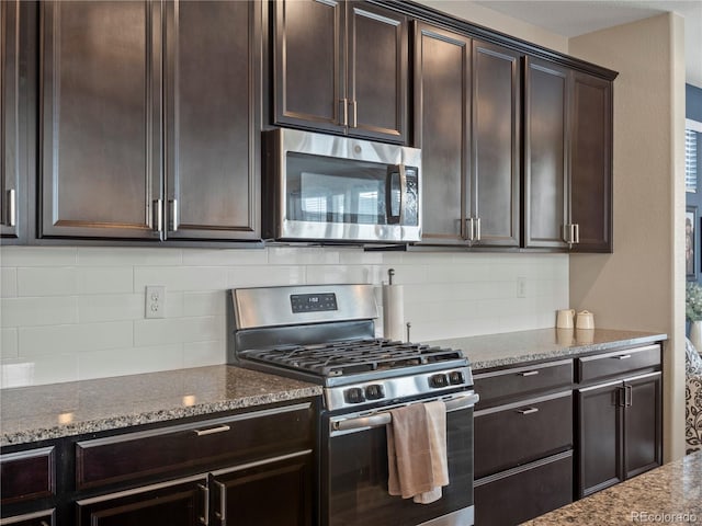 kitchen featuring dark brown cabinetry, appliances with stainless steel finishes, stone countertops, and backsplash