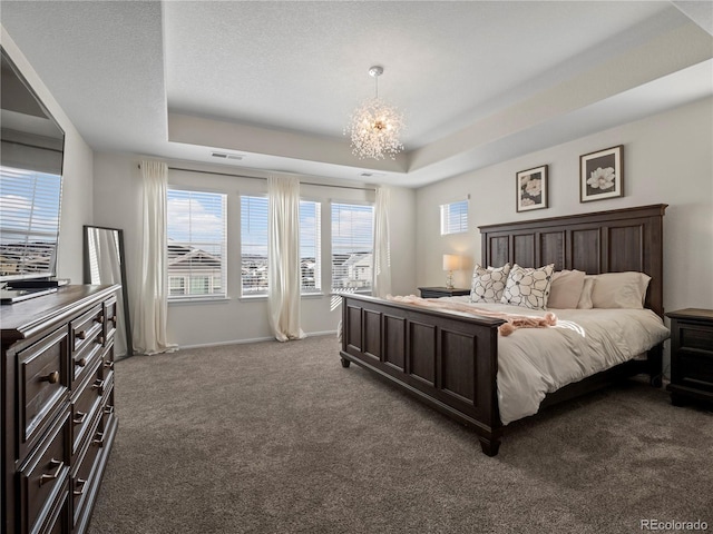 bedroom featuring an inviting chandelier, a tray ceiling, and dark colored carpet