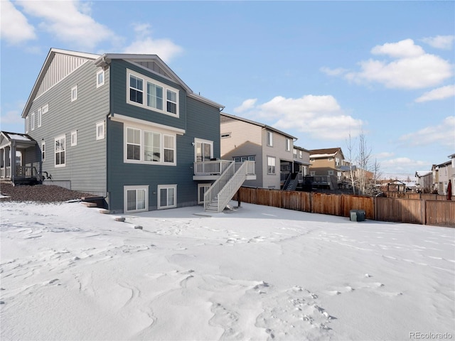 snow covered back of property featuring a deck