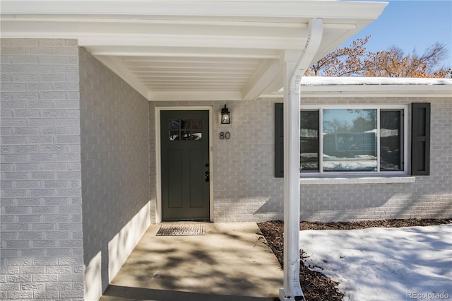 view of exterior entry featuring brick siding