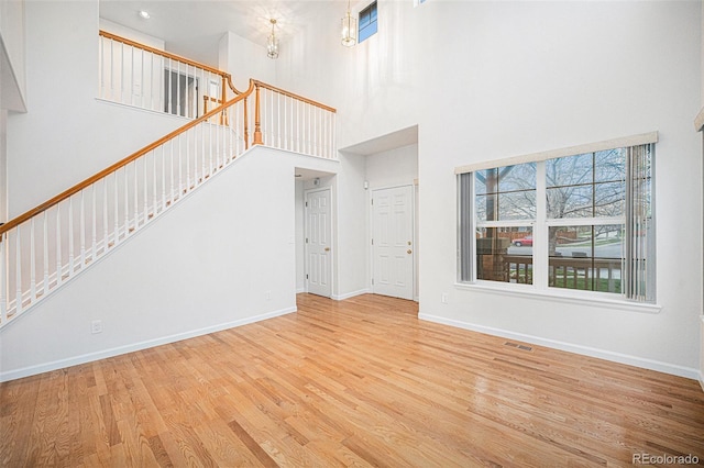 5607 S Gray St, Littleton, CO 80123 - unfurnished living room with baseboards, stairs, wood finished floors, and a towering ceiling