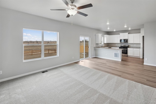 kitchen with recessed lighting, stainless steel appliances, baseboards, open floor plan, and light countertops