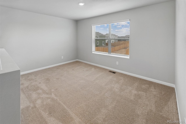 unfurnished room featuring carpet, visible vents, and baseboards