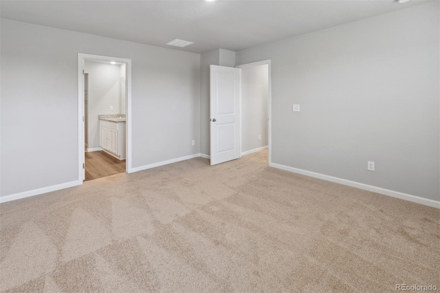 unfurnished bedroom with light carpet, visible vents, baseboards, and ensuite bathroom