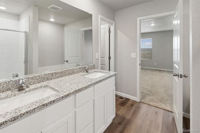 full bath with wood finished floors, a sink, visible vents, and baseboards