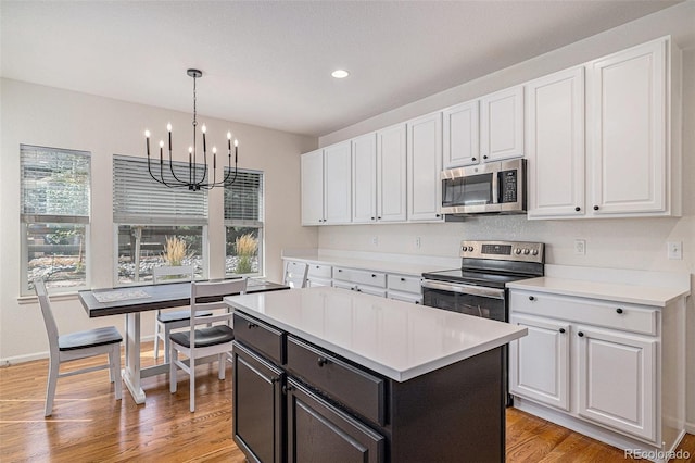 kitchen featuring stainless steel appliances, white cabinets, a chandelier, light countertops, and light wood-type flooring