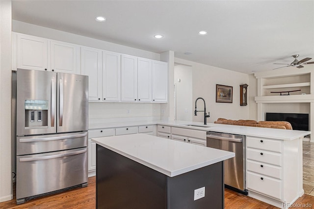 11973 Song Bird Hills St, Parker, CO 80138 - kitchen featuring appliances with stainless steel finishes, a peninsula, open floor plan, wood finished floors, and light countertops