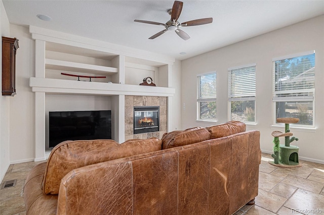 11973 Song Bird Hills St, Parker, CO 80138 - living room with a tile fireplace, a ceiling fan, stone tile floors, and built in shelves